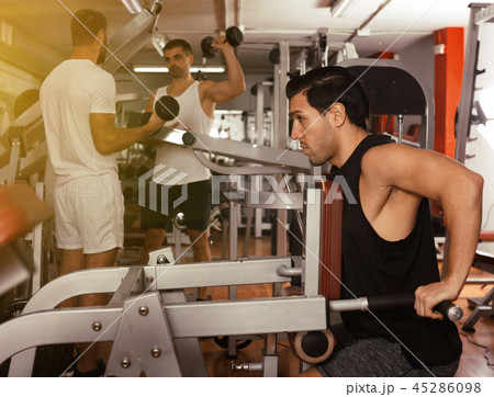 Guy training on fitness machine in gym Guy training on fitness machine in gym 45286098