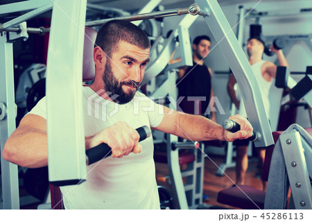 Guy training on fitness machine in gym Guy training on fitness machine in gym 45286113
