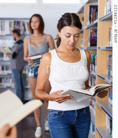 Female student browsing textbooks in library Female student browsing textbooks in library 45286122