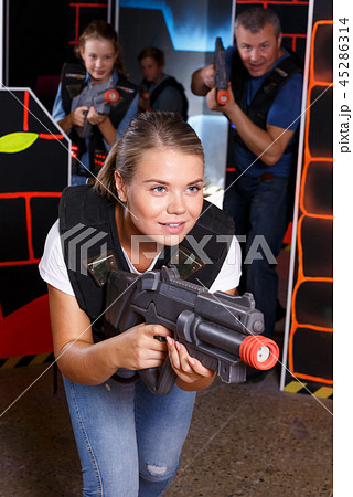 Young woman holding laser gun and playing lasertag game with family 45286314