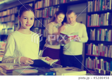 Portrait of intelligent preteen girl browsing textbooks in public library Portrait of intelligent preteen girl browsing textbooks in public library 45286458