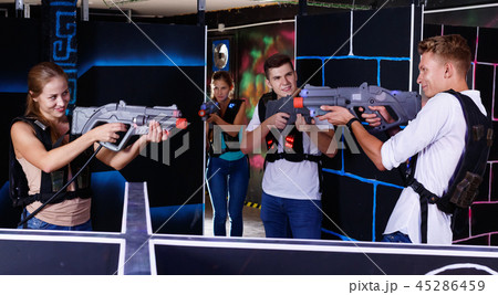 Laser tag players guys and girls playing in teams in dark laser tag room Laser tag players guys and girls playing in teams in dark laser tag room 45286459