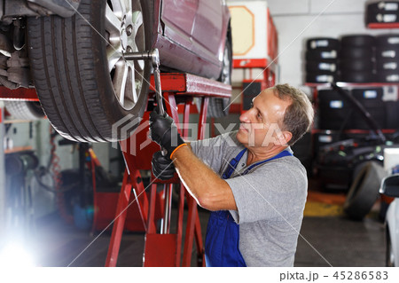 Mechanic installing car wheel after repair of balancing Mechanic installing car wheel after repair of balancing 45286583