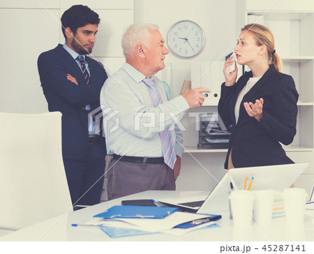 Mature businessman is chastising employees because of uncompleted work Mature businessman is chastising employees because of uncompleted work 45287141