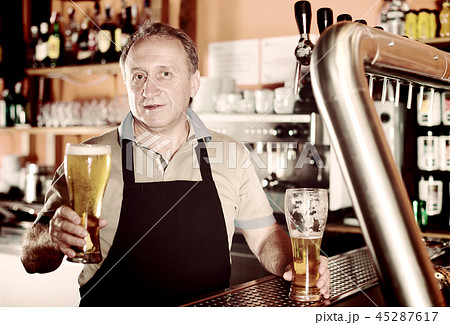 Barman is standing with golden beer Barman is standing with golden beer 45287617