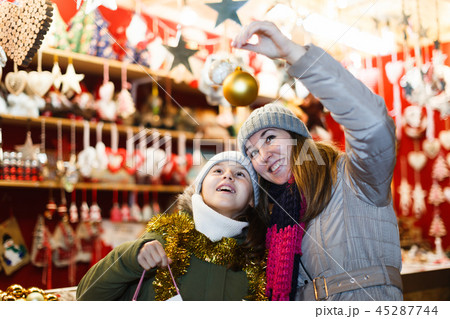 Young girl and her mother are choosing decorations for Christmas tree Young girl and her mother are choosing decorations for Christmas tree 45287744