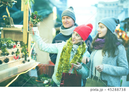 cheerful family couple with teen girl choosing Christmas decoration 45288738
