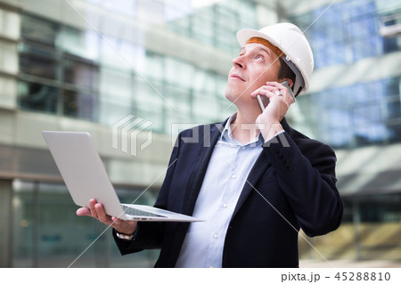 Smiling worker talking at mobile phone Smiling worker talking at mobile phone 45288810