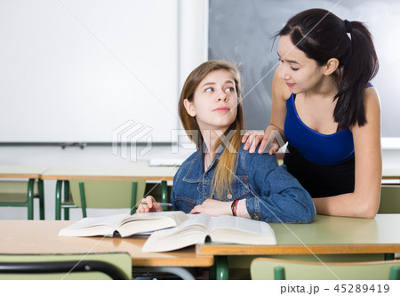 Girl is helping girlfriend with homework at the desk 45289419