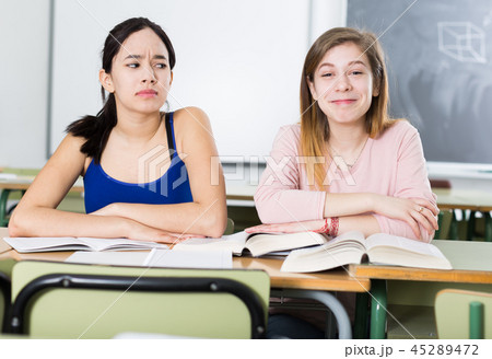 Portrait schoolgirl who is envying her successful girlfriend at the desk 45289472