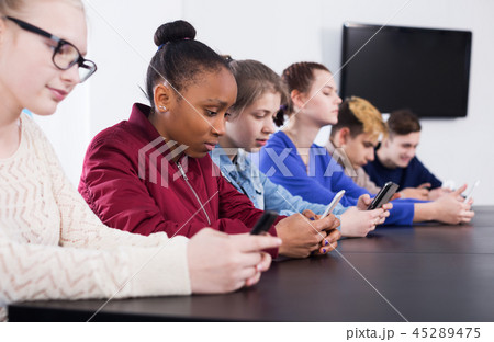 Male and female students playing with smartphones Male and female students playing with smartphones 45289475