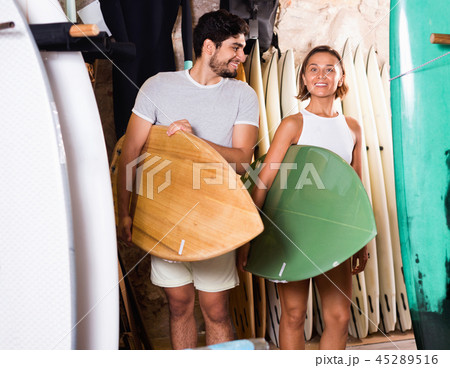 Couple of positive man with boards for surfing in the shop 45289516