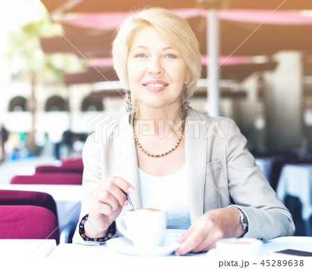 Portrait of elegant mature female who is enjoying of lunch with coffee 45289638