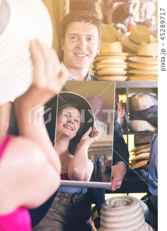 guy holding mirror and showing female his reflection in hats shopping mall 45289717