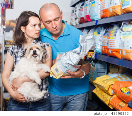 Portrait of family couple with dog choosing dry food in pet store Portrait of family couple with dog choosing dry food in pet store 45290322