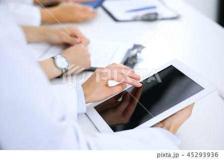 Doctor using tablet computer at medical meeting, closeup. Group of colleagues at the background 45293936