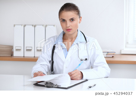Doctor woman writing papers at the desk in hospital office. Medicine and over work concept 45294037