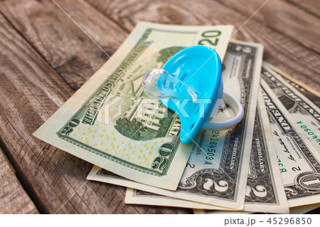 Blue pacifier on the background of money. Blue pacifier on the background of money. 45296850