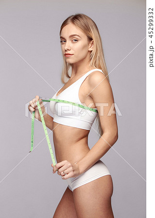 Portrait of beautiful young woman measuring her lfigure size with tape measure. 45299332