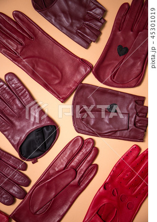 background of a variety of burgundy gloves on beige 45301019