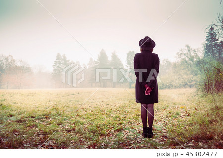 Girl in a coat and red gloves looks at the fog 45302477