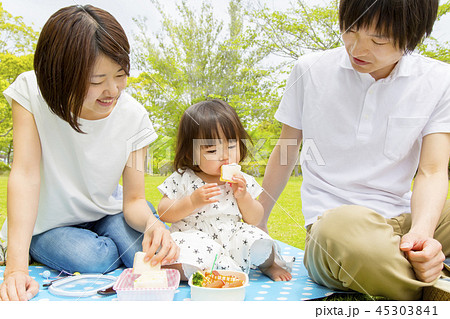 新緑の中 タンポポを持つ幼い娘を持ち上げる父の写真素材