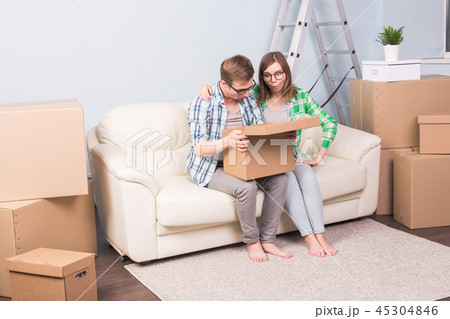 Relocation, apartment, real estate and moving concept - a couple of young people sitting on sofa and 45304846