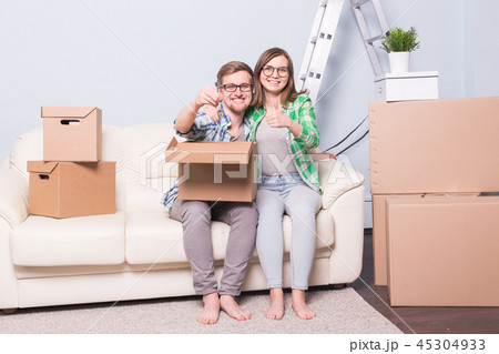 Moving, relocation and new home concept - young couple having fun on the couch surrounded with boxes Moving, relocation and new home concept - young couple having fun on the couch surrounded with boxes 45304933
