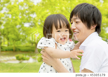 新緑の公園で幼い娘と一緒に遊ぶ若いお父さん。家族、親子、愛情、幸せ、育児、子育てイメージ 45305179