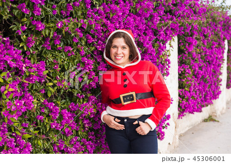 Christmas, holidays, humor and people concept - young happy woman smiling in christmas suit at 45306001