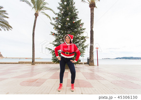 Christmas, holidays and humor concept - young happy woman have fun in christmas costume at summer 45306130