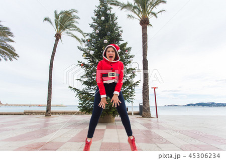 people, holidays and christmas concept - young funny and expressive woman dressed as santa claus 45306234