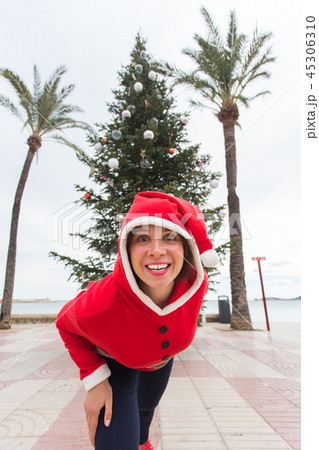 Christmas, holidays and humor concept - young happy woman have fun in christmas suit at summer near 45306310