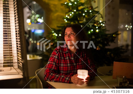 Holidays and people concept - Beautiful woman in cafe near Christmas tree background 45307316