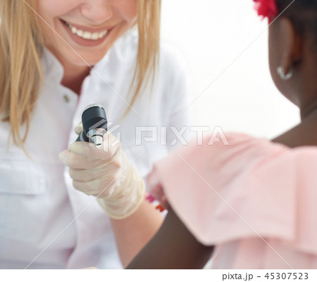 Female doctor checking skin of afro child with dermatoscope. 45307523