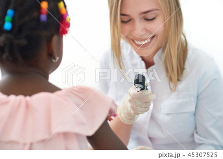 Smiling female doctor checking skin of little afro girl. 45307525