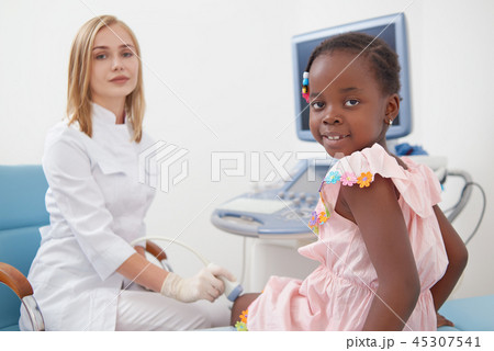 Cute afro girl sitting on bed during examines knee joints. 45307541
