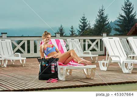 Hot girl lying on white lounger with towel in pink strip. 45307664