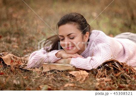 woman sitting in autumn park and reading book 45308521