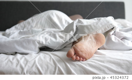 Man sleeping in bed feet relax on holidays. Close up of his foot 45324372