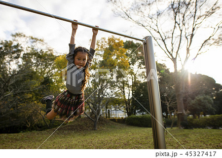 鉄棒で遊ぶ女の子の写真素材