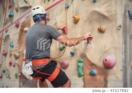 Young man practicing rock wall climbing indoors. 45327682