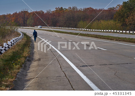 Tourist on the long road goes on the highway with a camera, journey concept background. 45331345