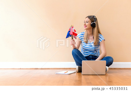Young woman holding English speaking country flags with laptop Young woman holding English speaking country flags with laptop 45335031