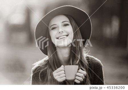 Beautiful girl with cup in the park. 45336200