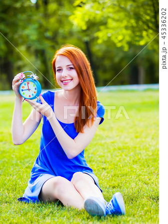 Redhead girl with clock in the park. Redhead girl with clock in the park. 45336202