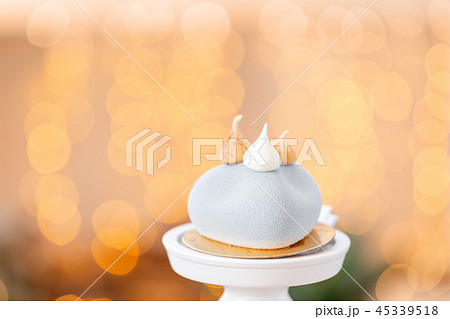 Mini mousse pastry dessert with gray velour on garland lamps bokeh background. Modern european cake 45339518