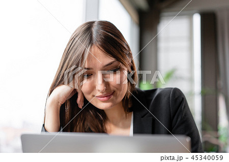 Young woman looks into the laptop screen. Girl blogging, browsing internet, chatting. Sits in coffee 45340059