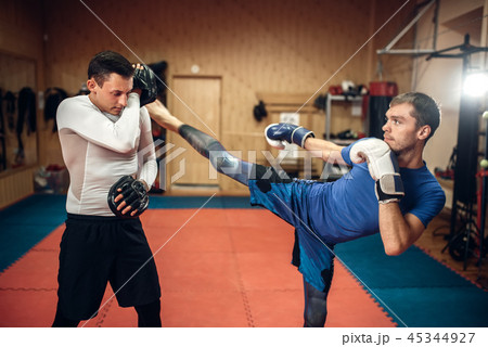 Kickboxer practicing kicking with personal trainer Kickboxer practicing kicking with personal trainer 45344927