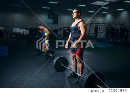 Two weightlifters doing exercise with barbells 45344976